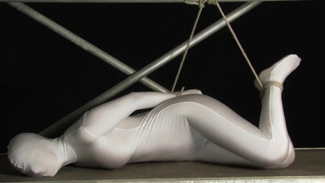 Babe wrapped in white zentai suit enjoys to be bondaged to a metal pole