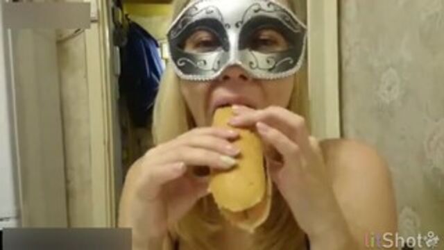 Beautiful masked girl eats a hotdog with her shit